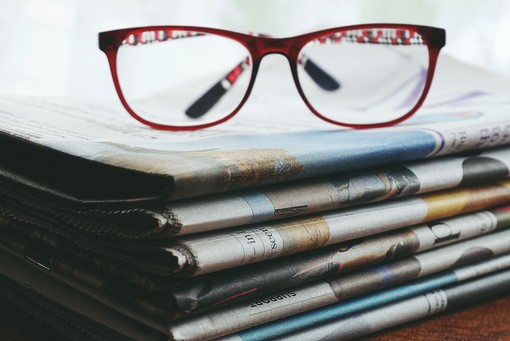 Symbolbild Serviceleistung Online-Abo Handelszeitung und Bilanz Brille liegt auf Zeitungsstapel